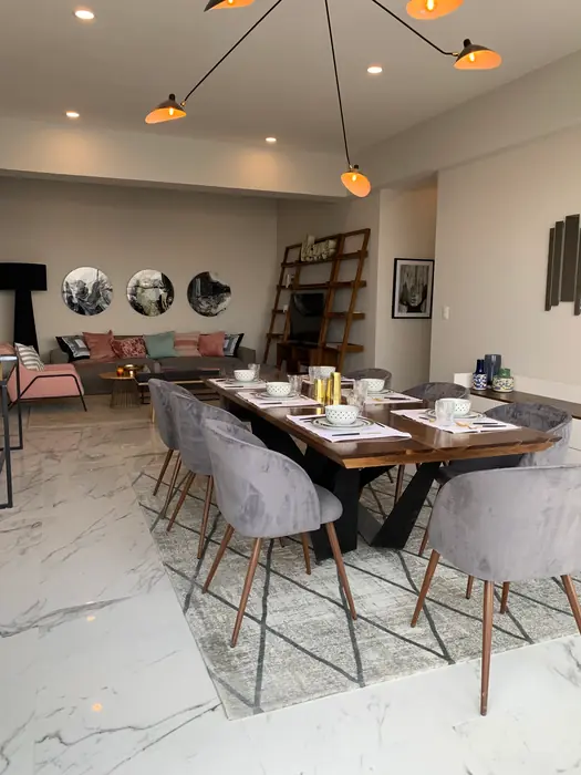 Comedor para ocho con sillas grises bajo lámpara de brazos