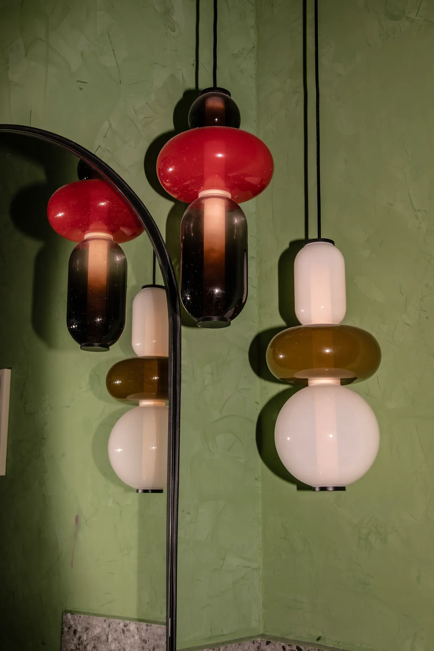 Lámparas de vidrio de colores sobre muro verde