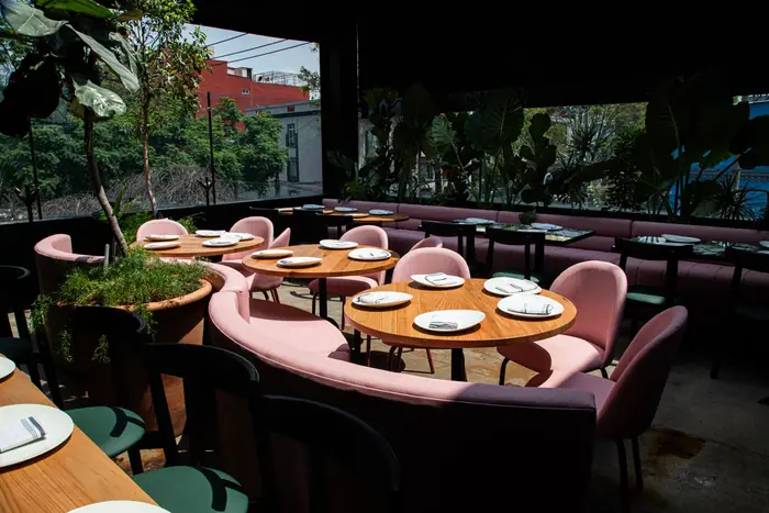 Terraza con vegetación y bancas rosas