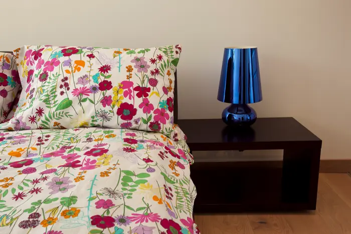 Recámara con lámpara azul y colcha floral