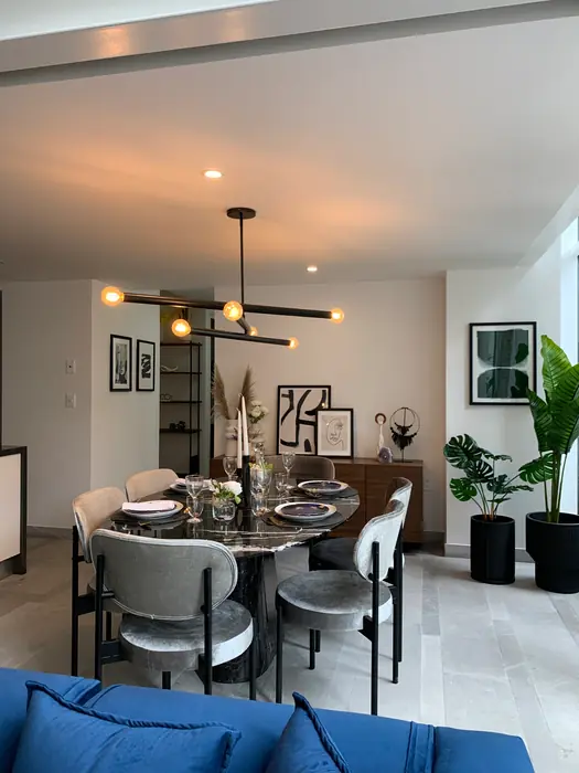Comedor con lámpara lineal, sillas tapizadas y plantas