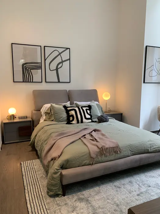 Recámara con cabecera tapizada, textiles en verde y rosa y arte gráfico