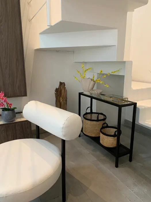 Silla blanca tapizada y consola junto a la escalera