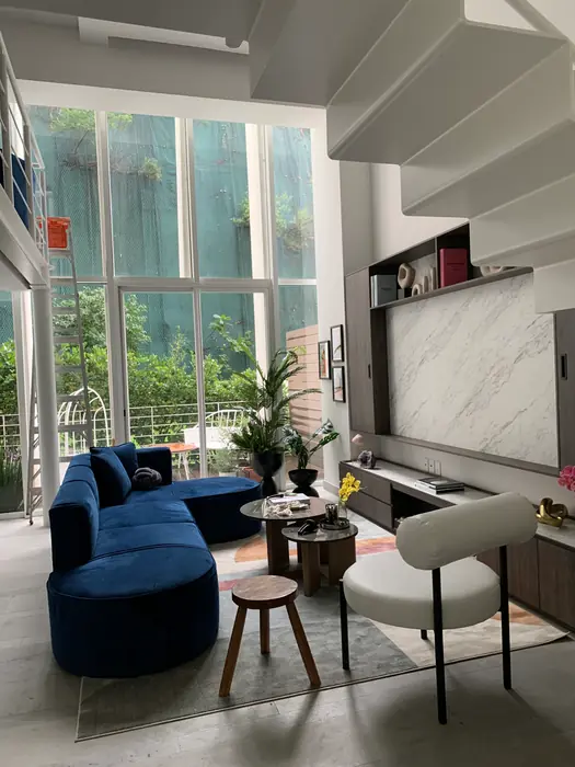 Estancia de doble altura con ventanal al jardín y mueble de TV en mármol
