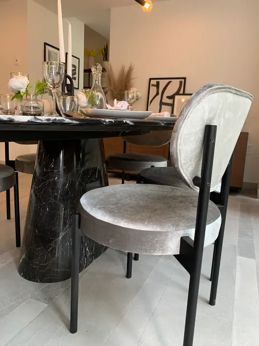 Mesa de comedor en mármol oscuro con sillas de terciopelo gris