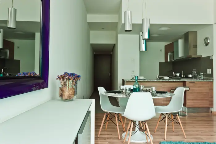 Comedor con sillas blancas y espejo morado
