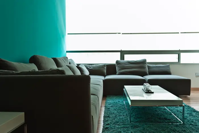 Sala con sofá gris y muro turquesa