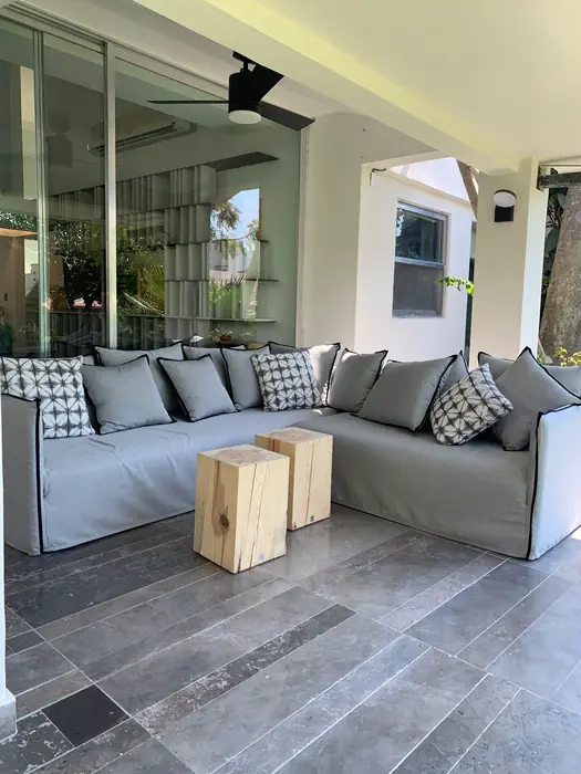 Sala de terraza con sofá gris y mesas de madera