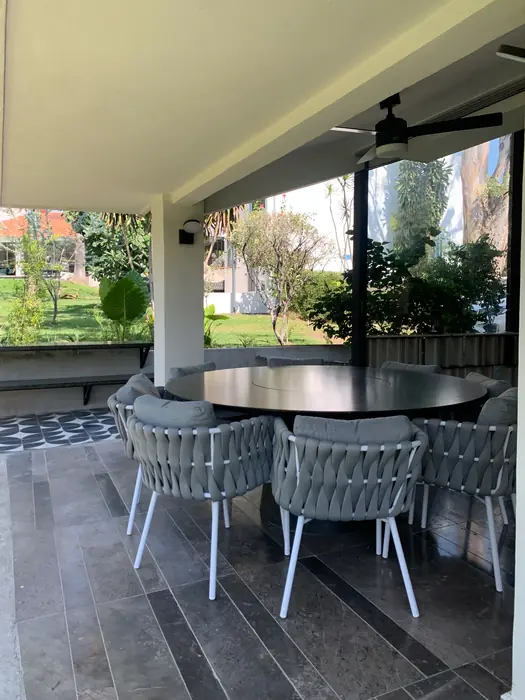 Terraza con comedor exterior de sillas tejidas frente al jardín