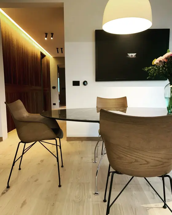 Desayunador con mesa de cristal, sillas de madera y lámpara blanca