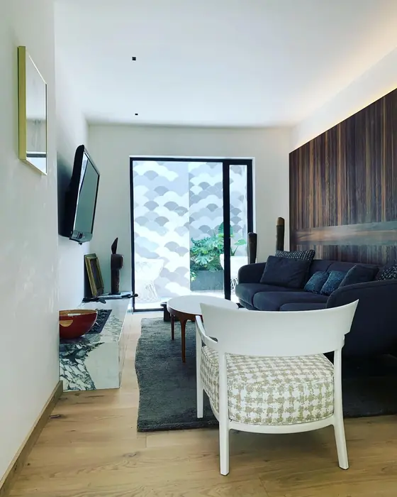 Estancia con sillón blanco tejido y celosía al fondo