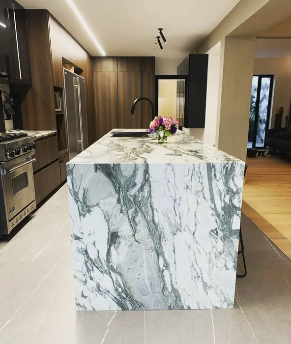 Cocina con isla de mármol veteado y gabinetes de nogal