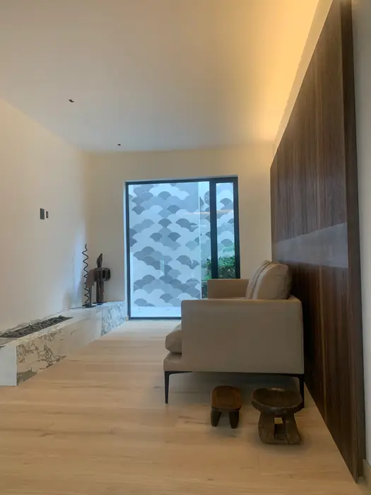 Sala de TV con lambrín de nogal y ventana con celosía