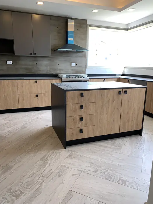Cocina con isla de madera y cubierta negra, campana de acero