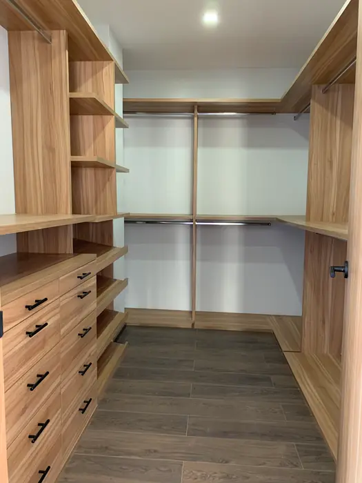 Pasillo de vestidor con cajoneras y barras de colgado