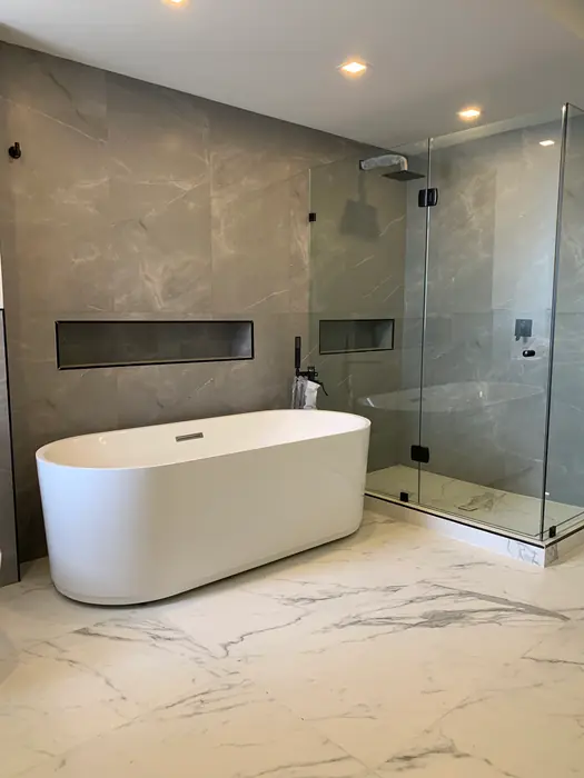Baño principal con tina exenta, regadera de cristal y piso de mármol