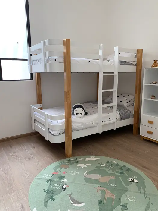 Recámara infantil con literas de madera y tapete de mapamundi