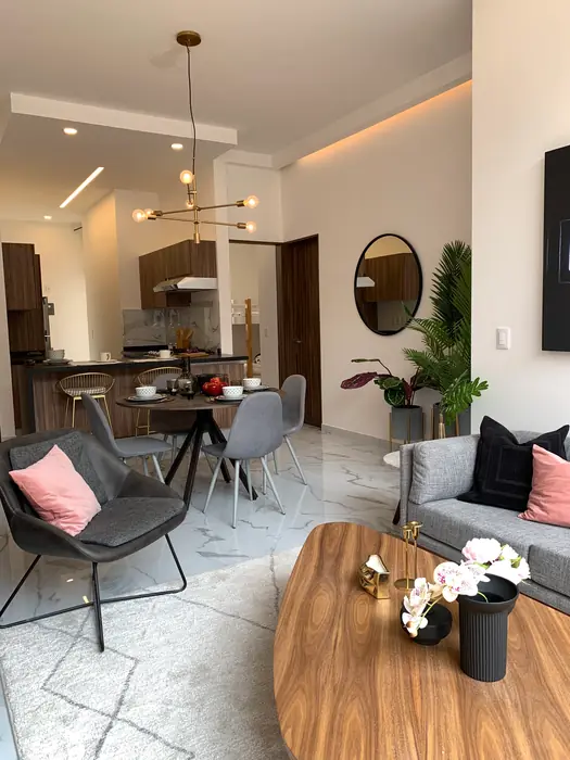 Estancia abierta con mesa de madera, sillones y comedor al fondo