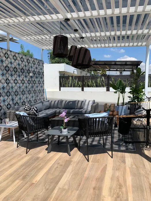 Sala exterior bajo la pérgola con lámparas de fibra negra