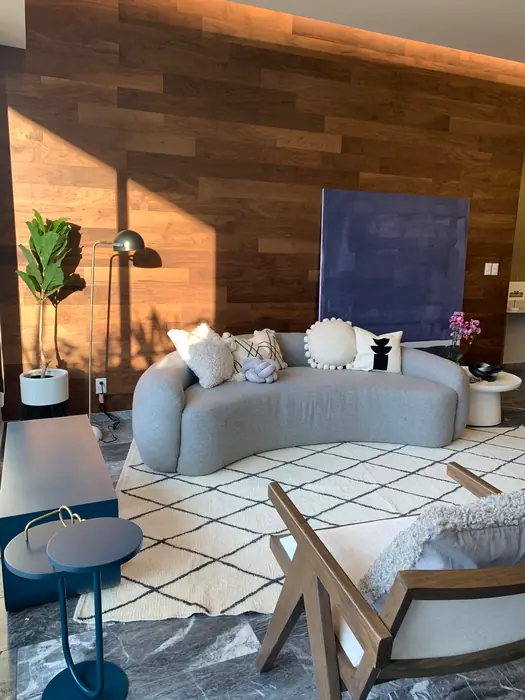 Sofá curvo gris frente a muro de madera con arte azul, Villa Fiori