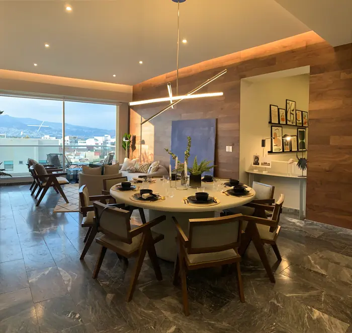 Comedor redondo con sillas de madera y vista panorámica al atardecer